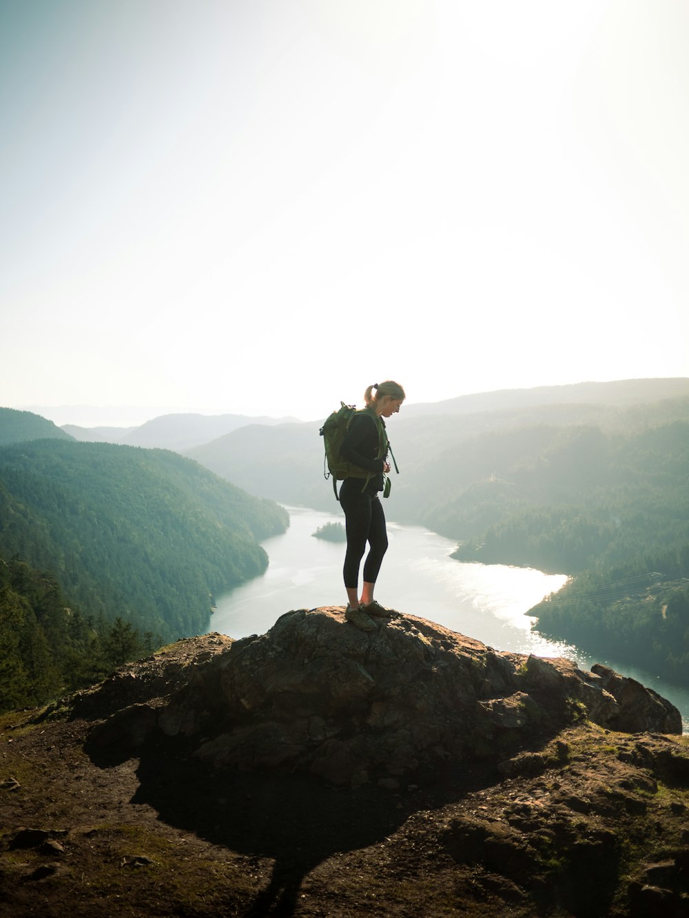 man in black jacket standing on rock near body of water during daytime