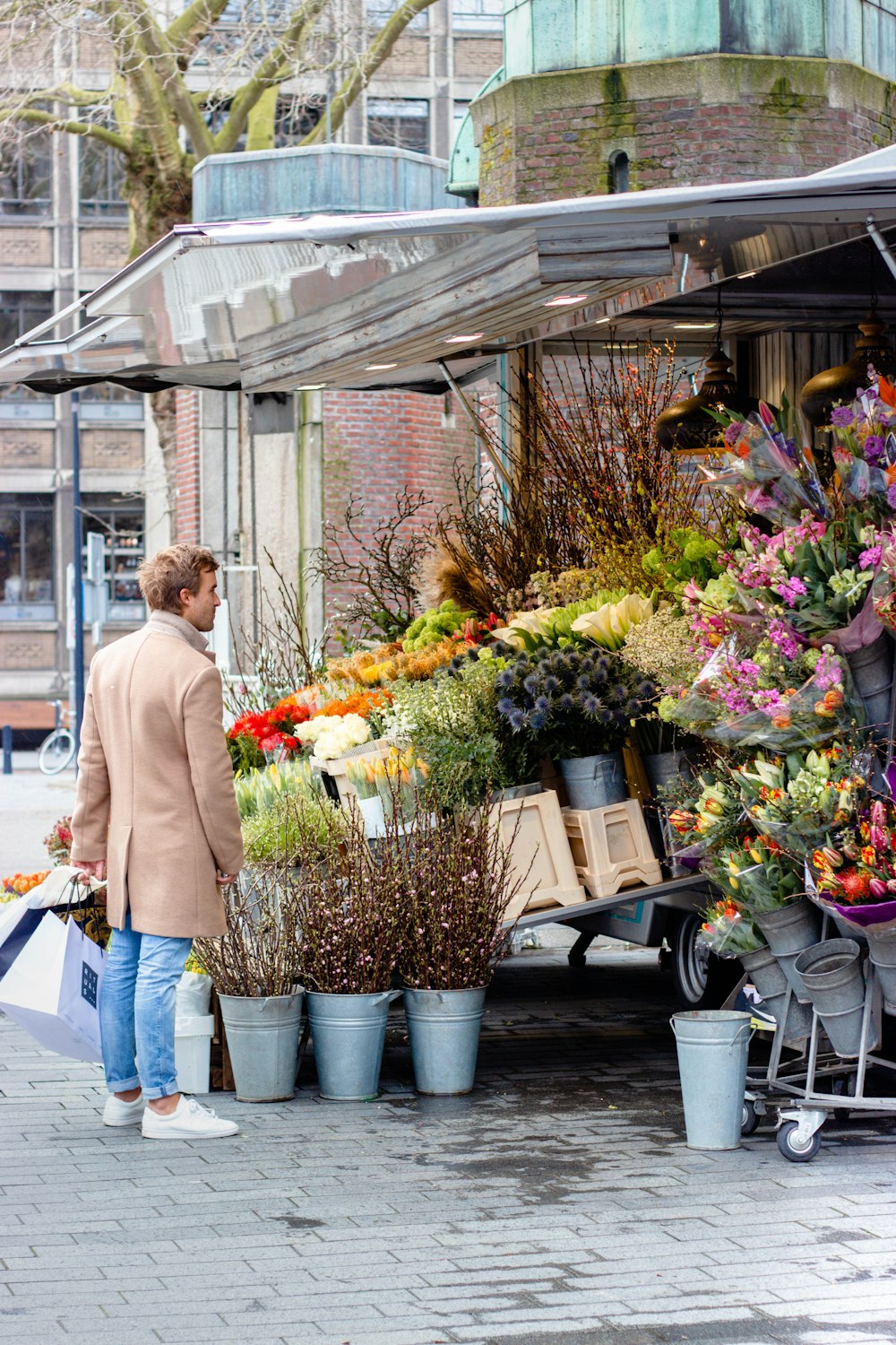 woman in white long sleeve shirt and blue denim jeans standing in front of flowers