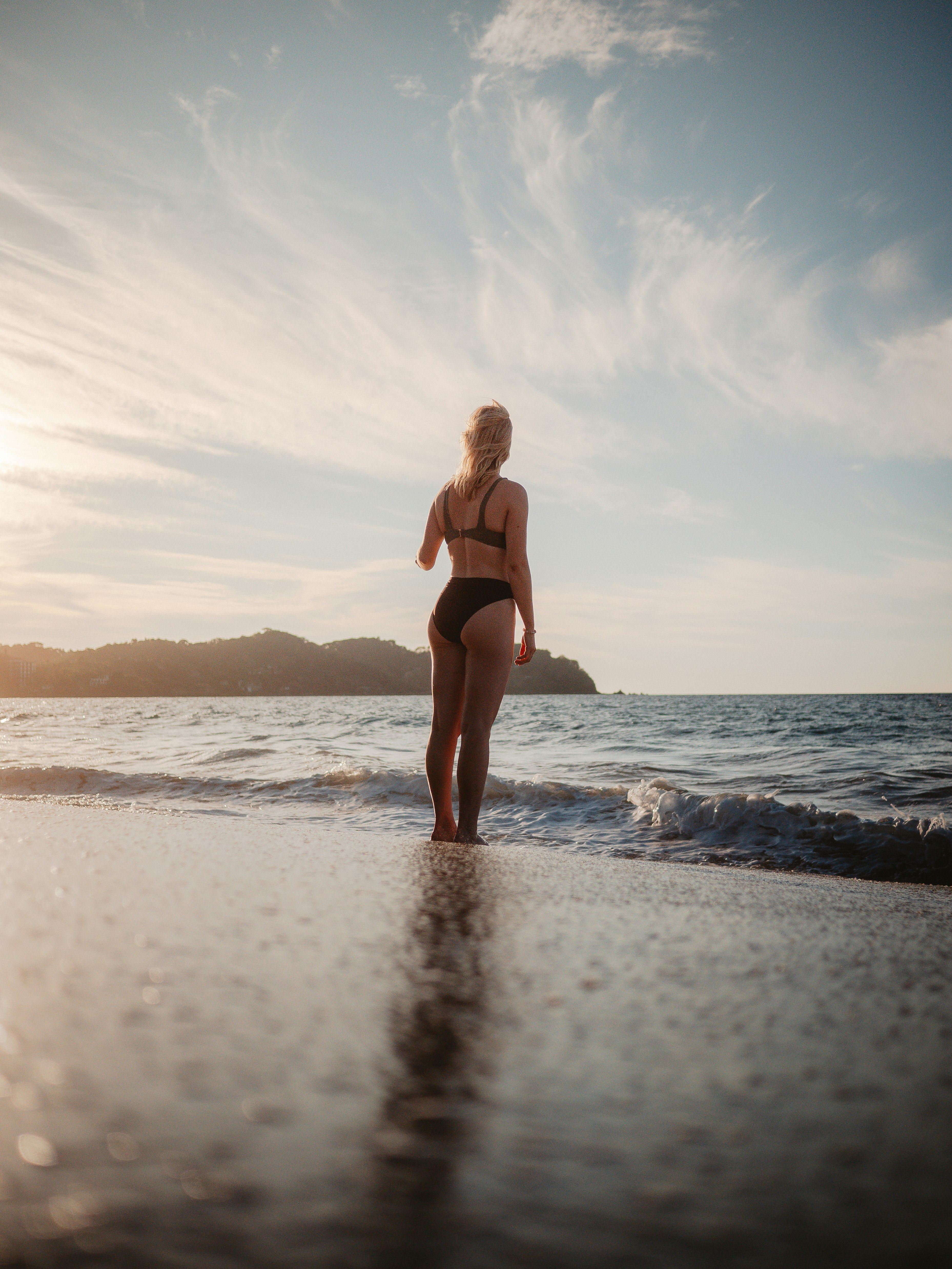 woman in black bikini standing on beach during daytime