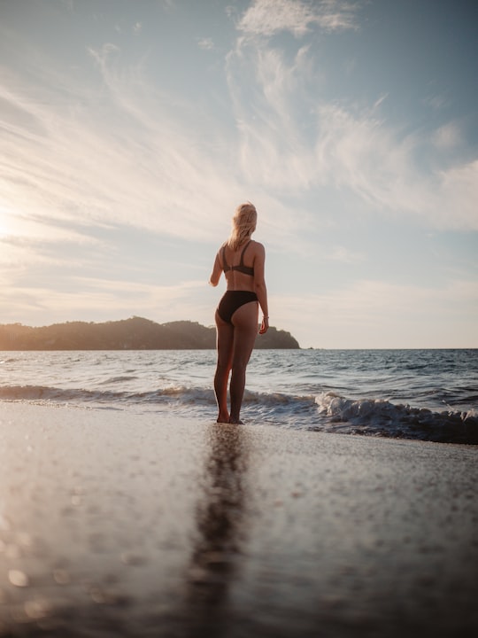 woman in black bikini standing on beach during daytime in Sayulita Mexico
