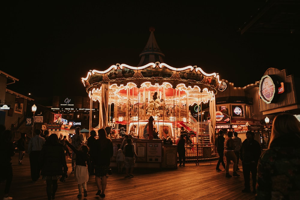 people standing near lighted carousel during night time