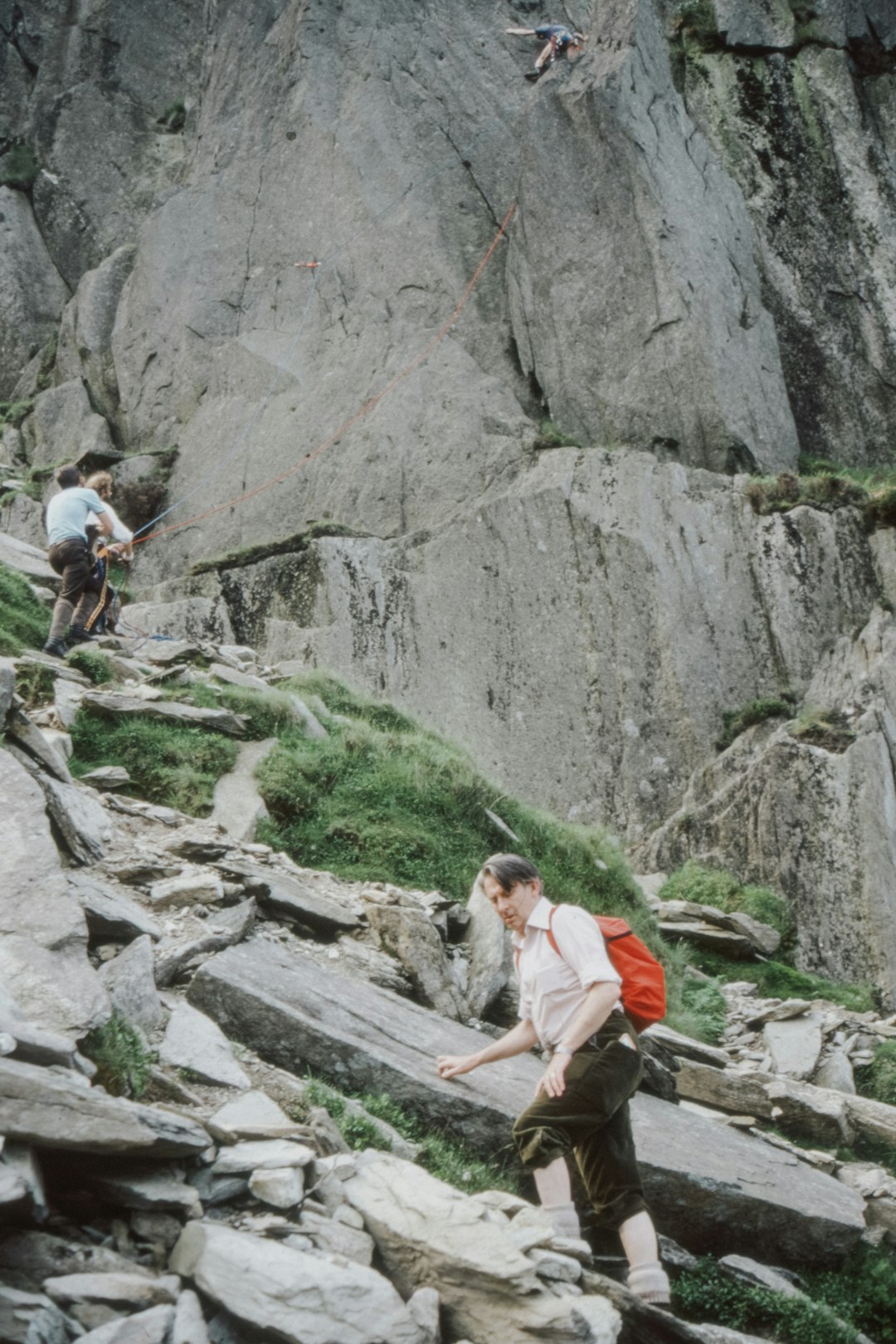 woman in white t-shirt and orange shorts standing on gray rock during daytime