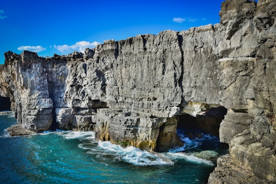 gray rocky mountain beside blue sea under blue sky during daytime in Sintra-Cascais Natural Park Portugal