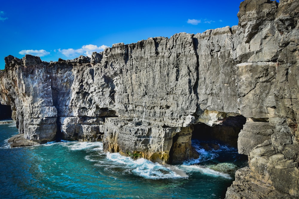 gray rocky mountain beside blue sea under blue sky during daytime