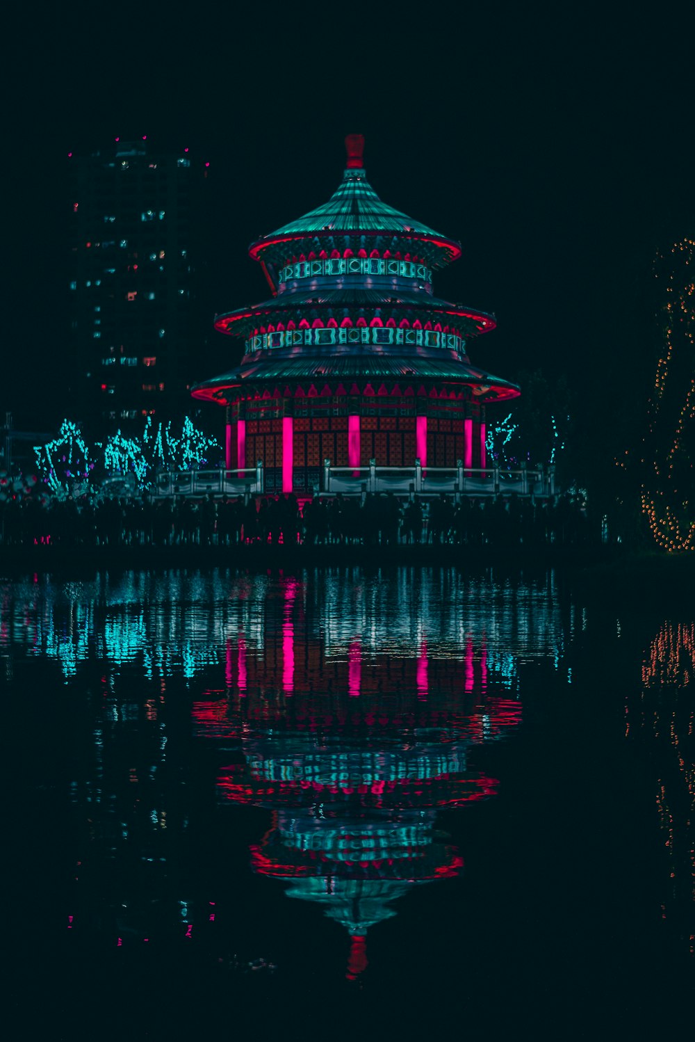 green and red lighted building near body of water during night time