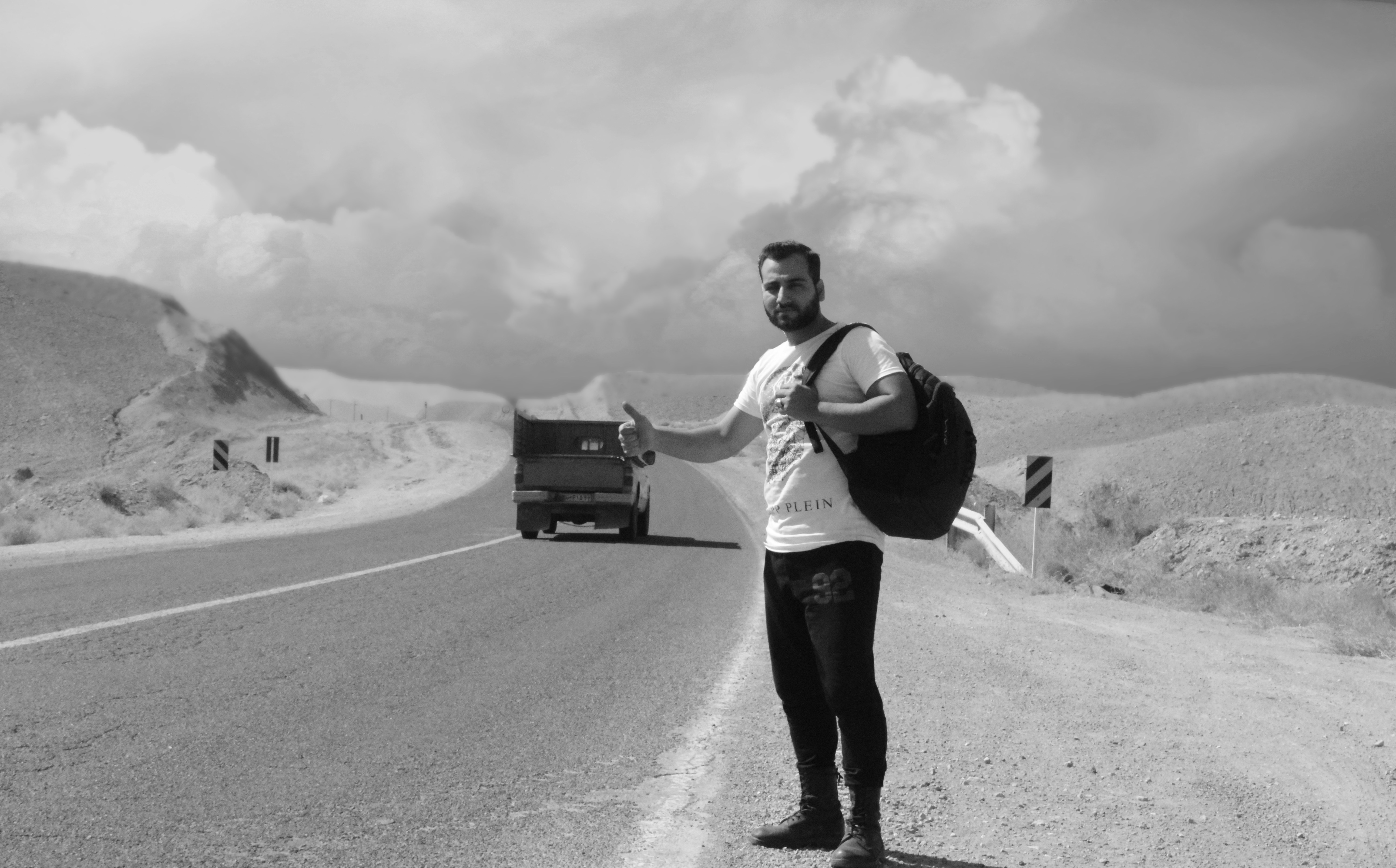 man in white long sleeve shirt and black pants standing on road