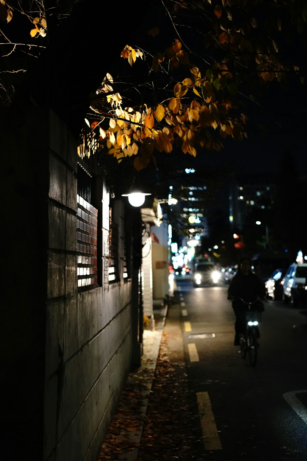Hombre en chaqueta negra montando en bicicleta en la acera durante la noche