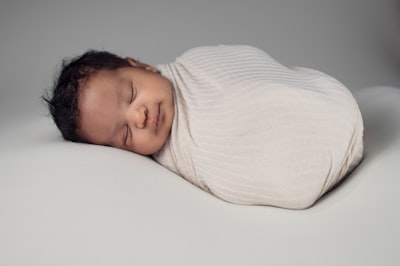 woman in white knit sweater lying on bed baby teams background