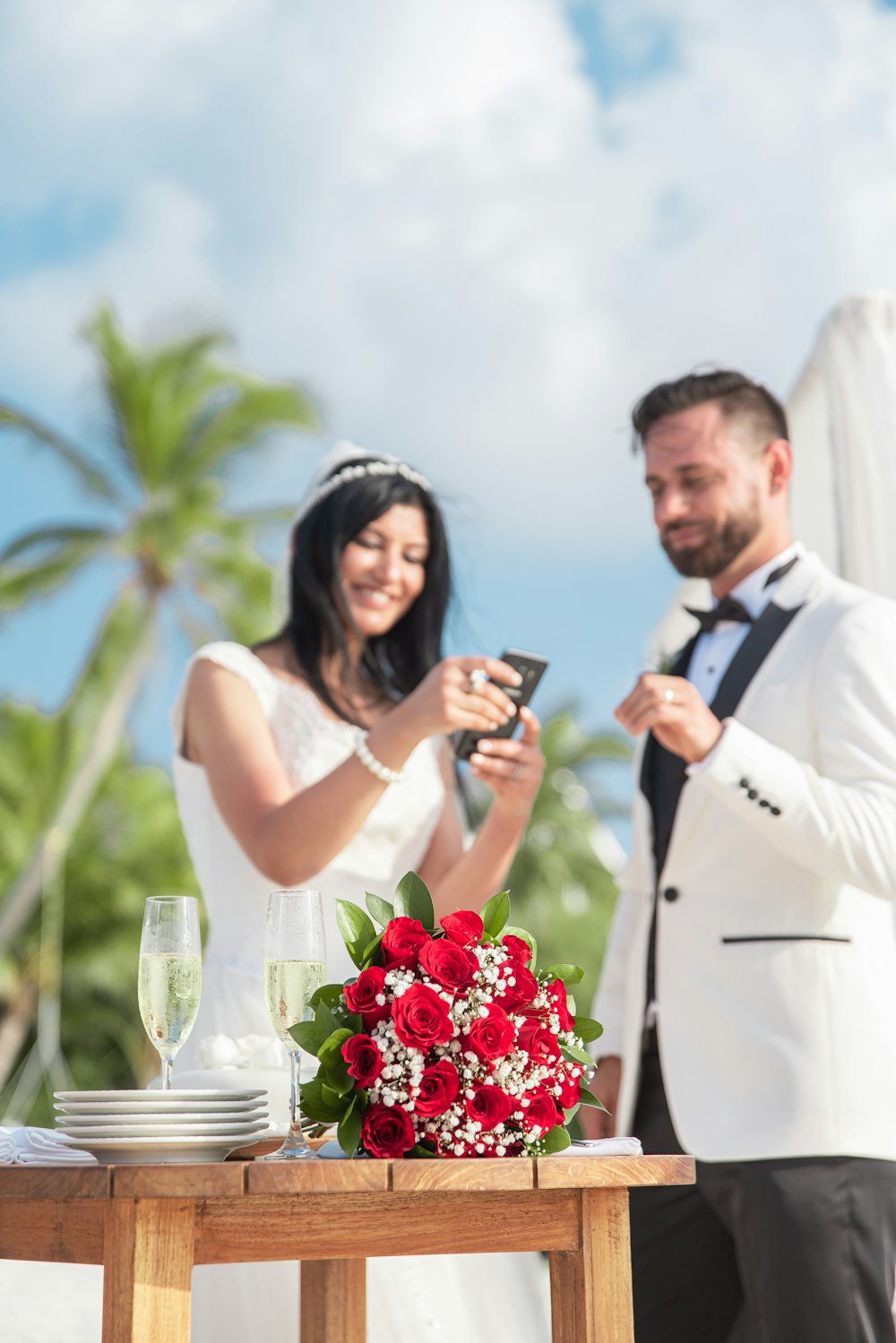 man in white suit jacket holding woman in white sleeveless dress