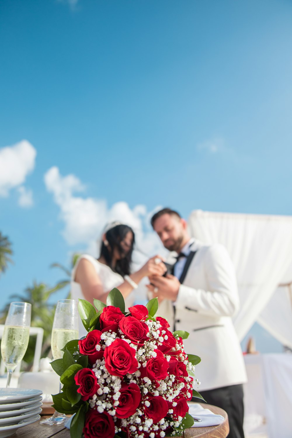 Frau im weißen Hochzeitskleid mit rotem Rosenstrauß