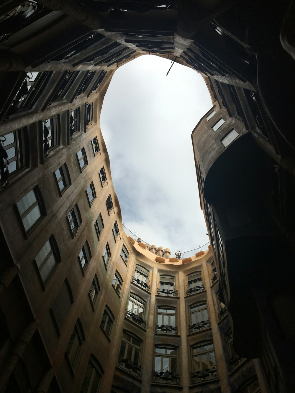 low angle photography of brown concrete building under white clouds during daytime