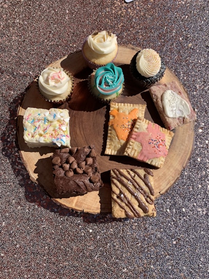 A colorful assortment of freshly baked cookies and cupcakes on a rustic wooden table.