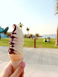 A family enjoying colorful soft serve cones together on a sunny park bench near the food truck.
