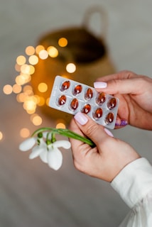person holding silver blister pack of red pills