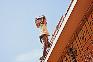 A worker carefully lifting and repositioning classic red clay roof tiles.