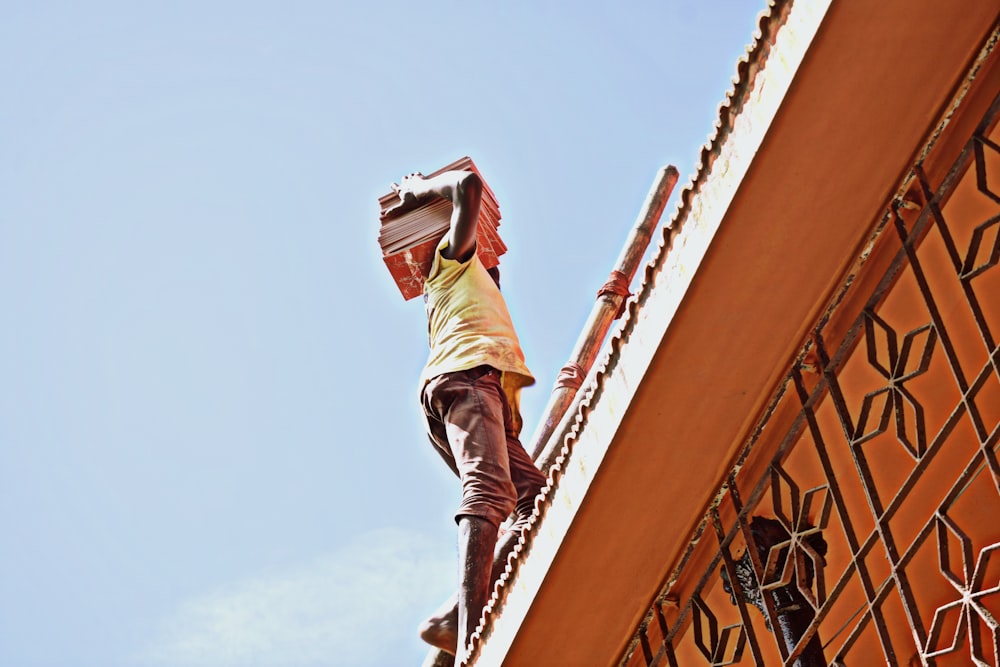 man in gray shirt and brown pants jumping on orange metal railings during daytime