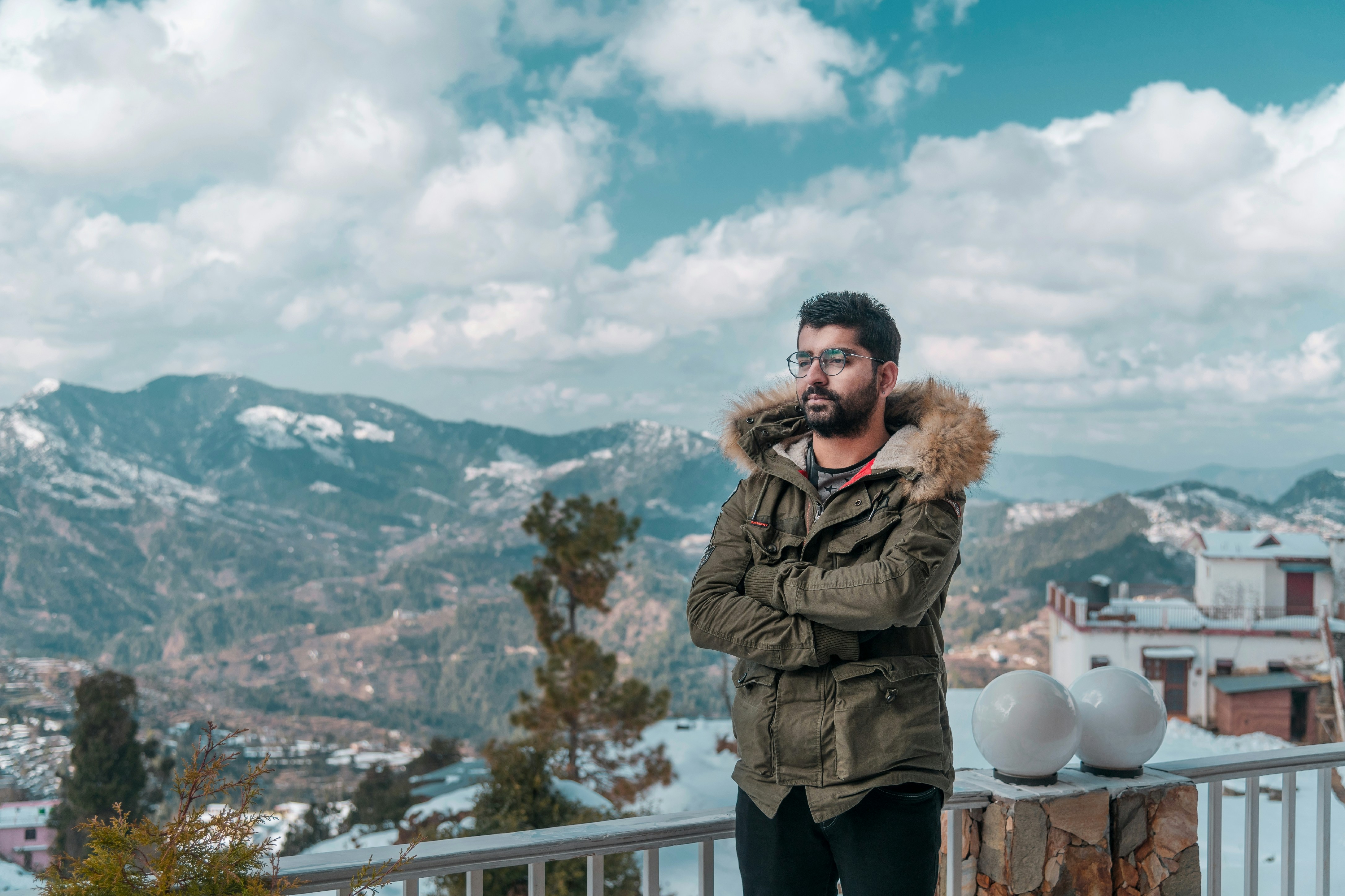 woman in brown parka jacket standing on white wooden fence during daytime