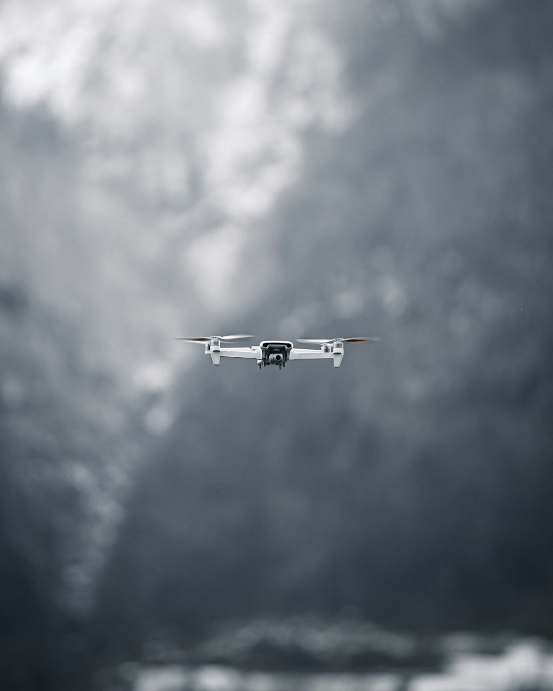 white and black airplane flying under white clouds during daytime