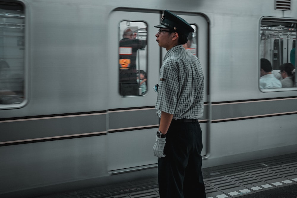 man in black hat standing in front of white train