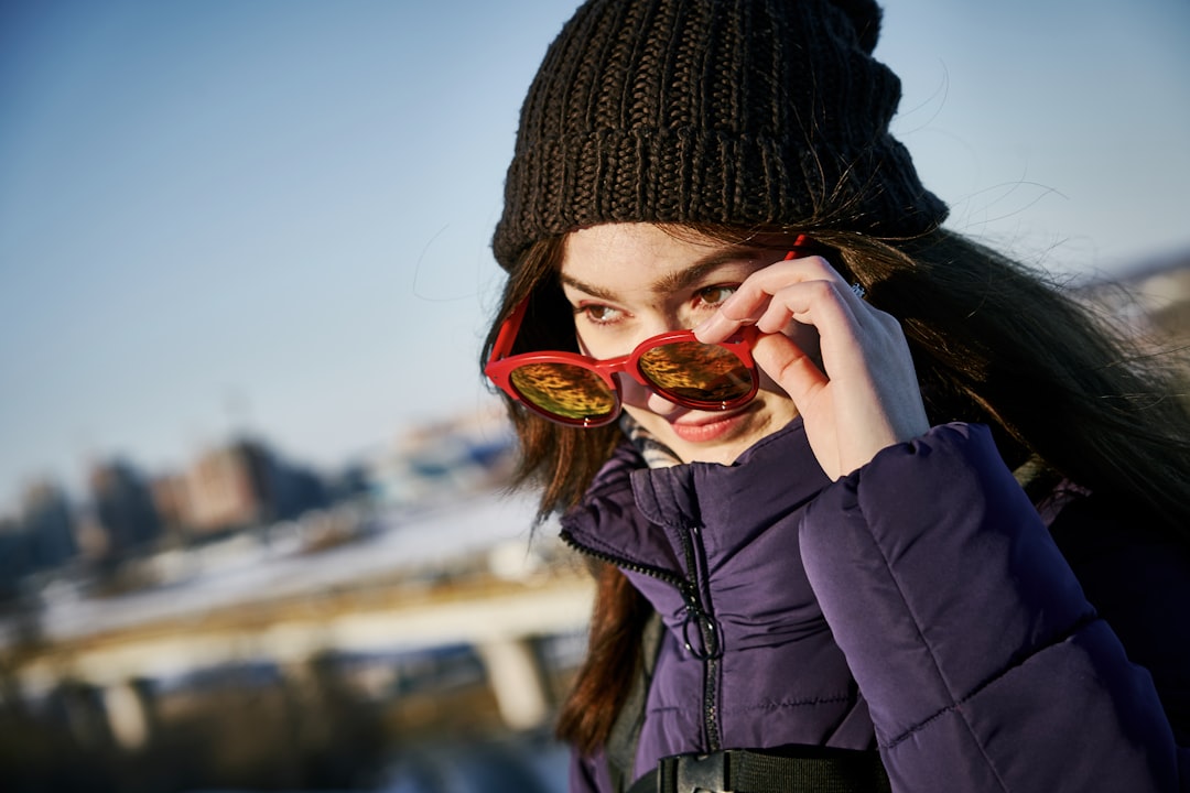 woman in black knit cap and black jacket holding red heart shaped ornament