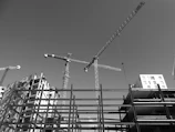 A panoramic view of the Heragon City construction site with cranes and workers under a clear sky