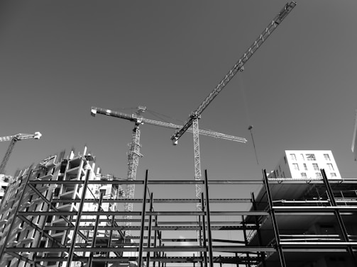 Modern infrastructure development with cranes and concrete structures under a clear sky.