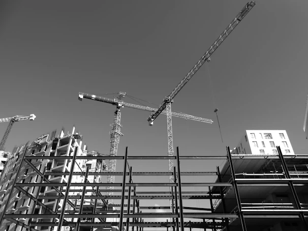 An expansive view of a real estate development site with cranes and electrical infrastructure being installed under a clear blue sky.