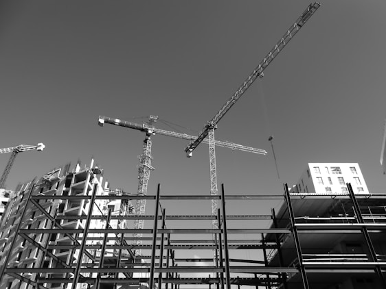 A panoramic view of a large-scale urban development project under construction, showcasing cranes and modern architecture against a clear sky.