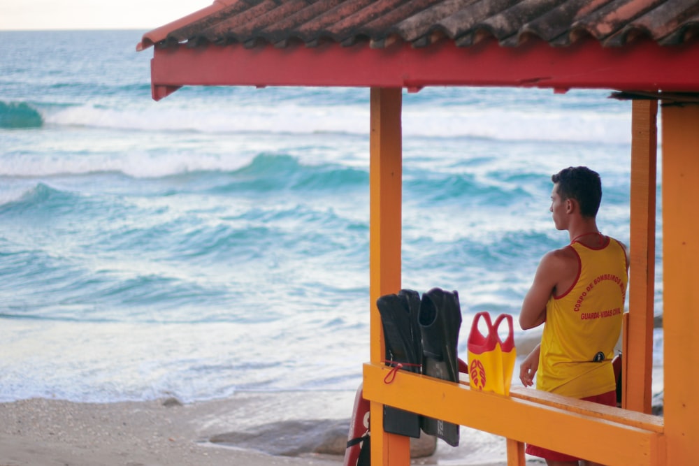 woman in white tank top sitting on orange wooden chair on beach during daytime