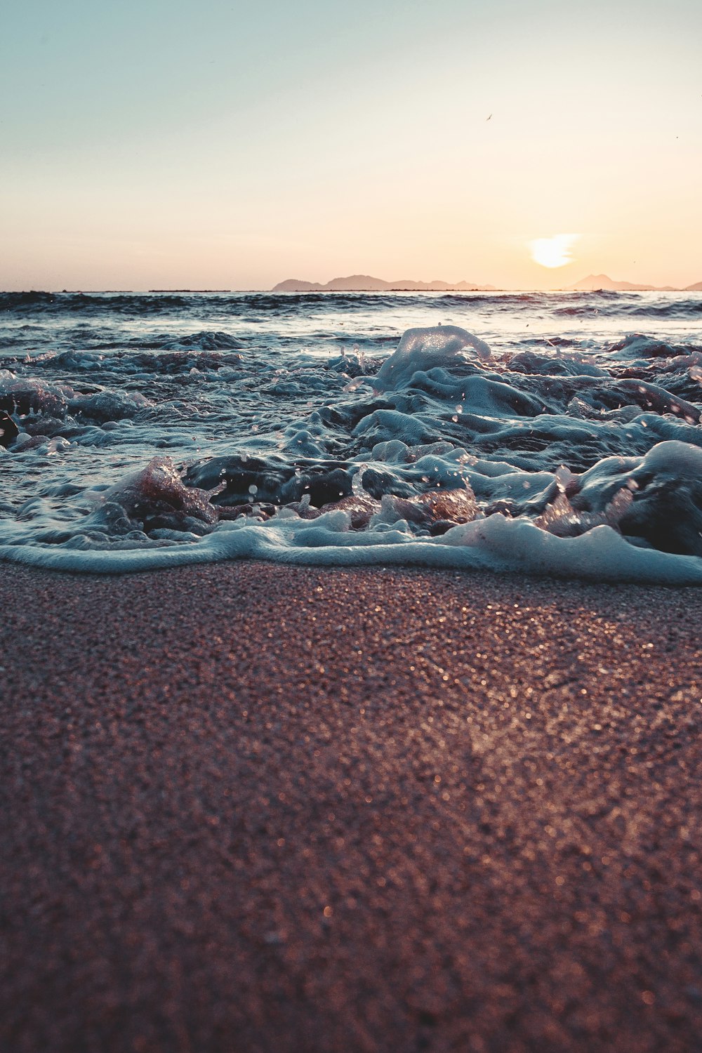 sea waves crashing on shore during sunset