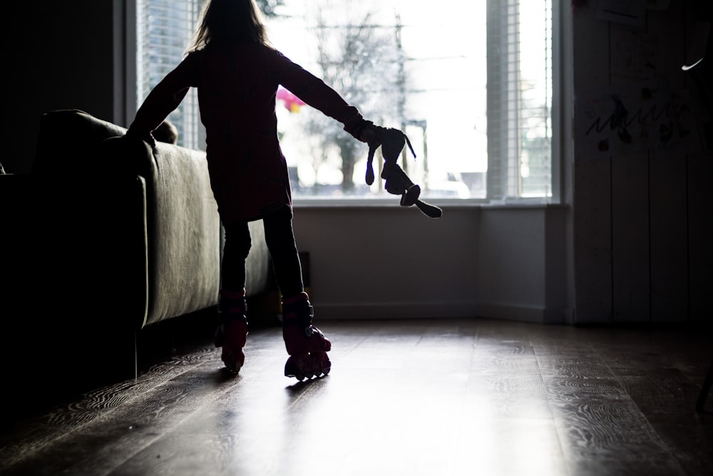 woman in black long sleeve shirt and gray skirt standing on brown wooden floor