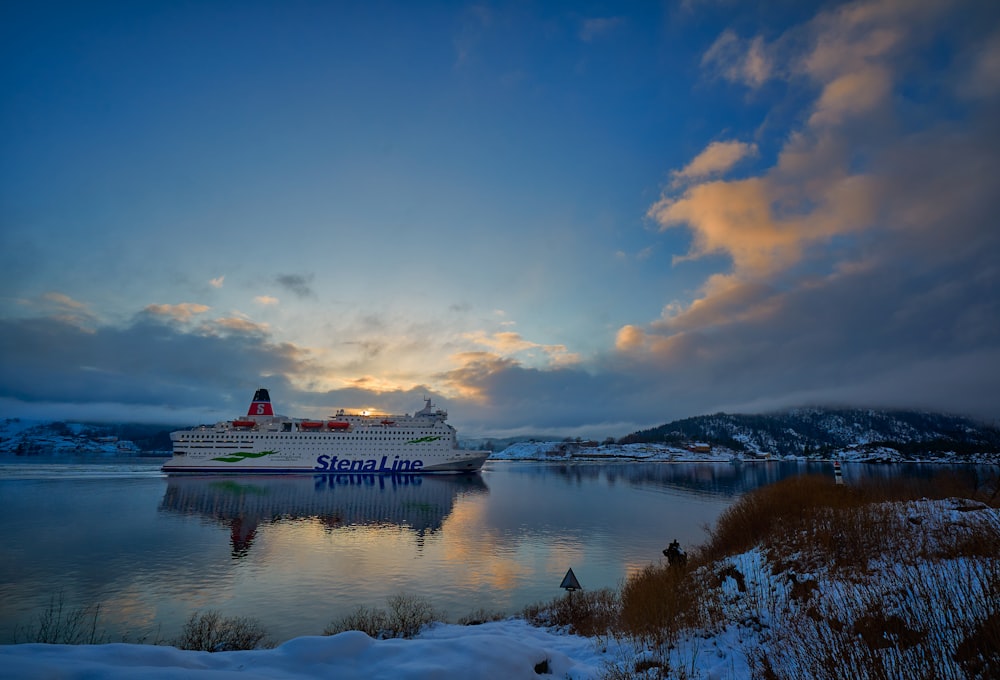 navio branco e azul no lago sob o céu azul e nuvens brancas durante o dia