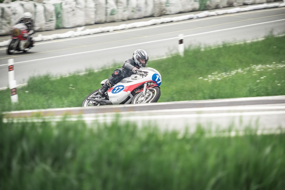 man riding blue and white motorcycle on road during daytime