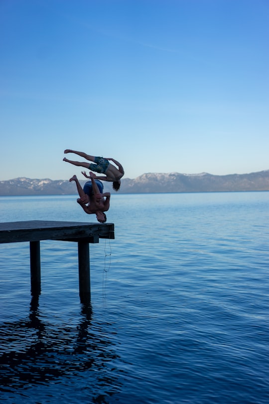 person in black shorts sitting on brown wooden dock during daytime in Lake Tahoe United States