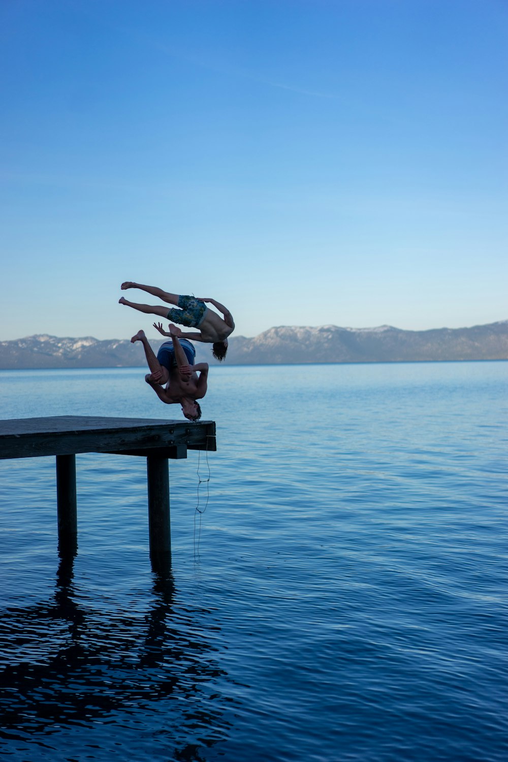 person in black shorts sitting on brown wooden dock during daytime