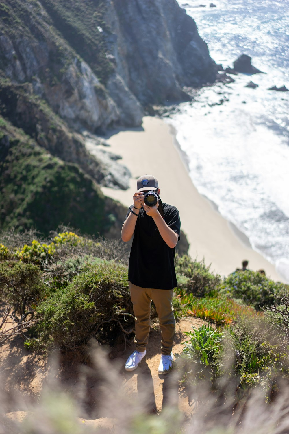 woman in black t-shirt and brown shorts holding black dslr camera standing on green grass