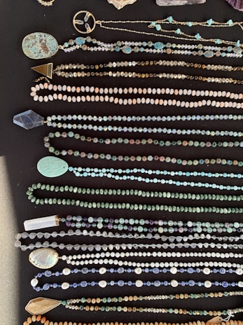 A collection of colorful stone necklaces laid out on a rustic wooden table.