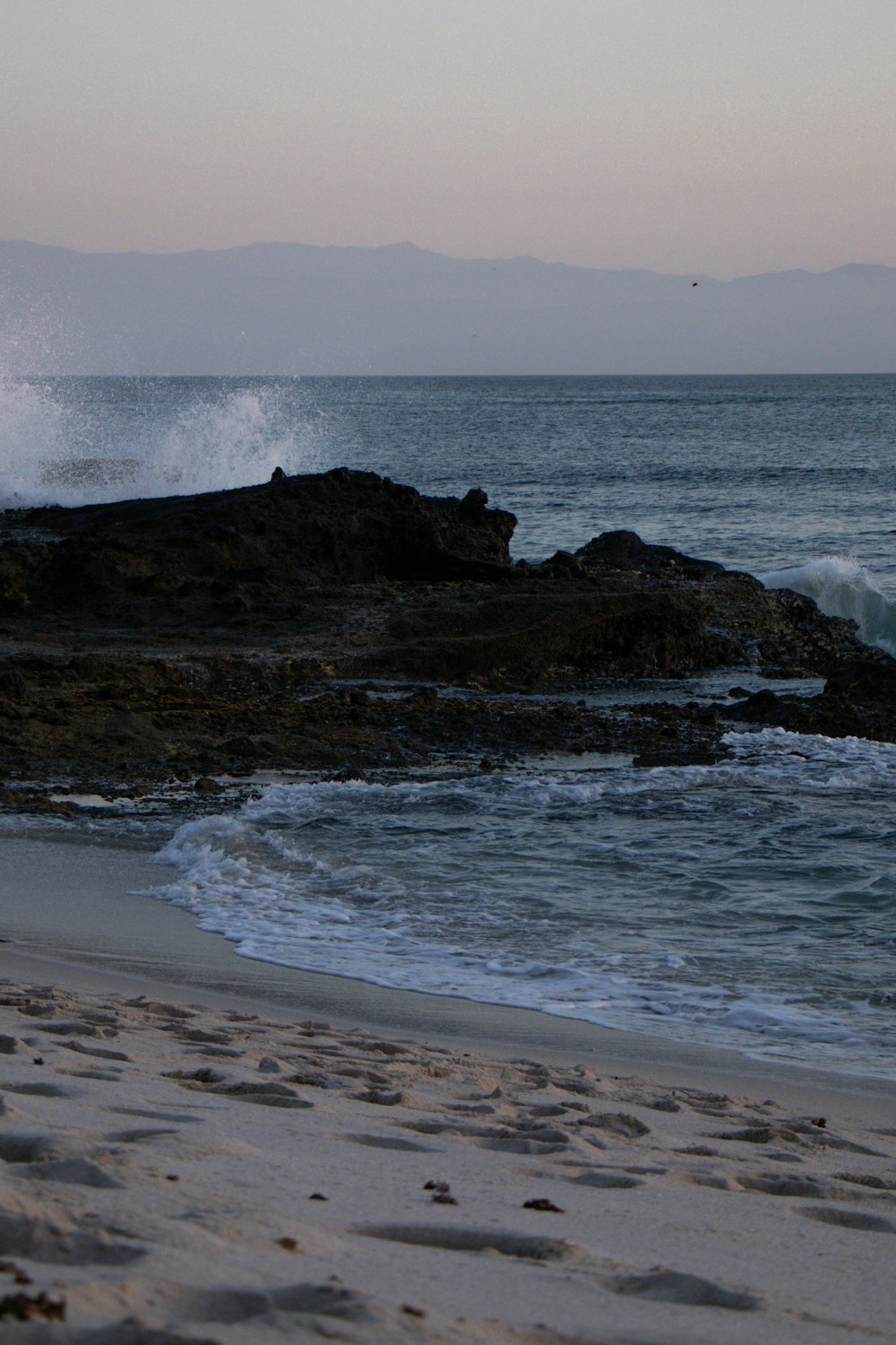 ocean waves crashing on brown rock formation during daytime