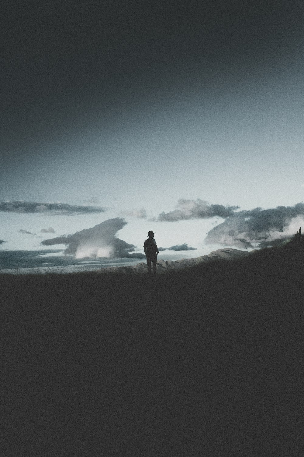 silhouette of person standing on rock formation during night time