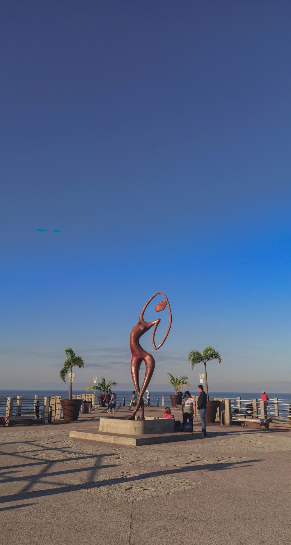 Statue de flamant rose en bois brun près d’un plan d’eau pendant la journée