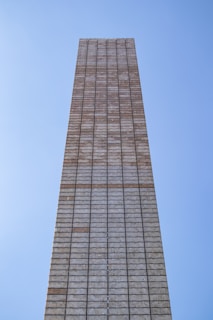 Team of workers laying bricks methodically under a clear sky.