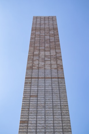 Team of workers laying bricks methodically under a clear sky.
