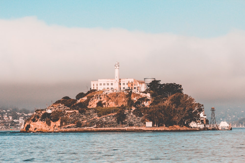 white concrete building on brown rock formation near body of water during daytime