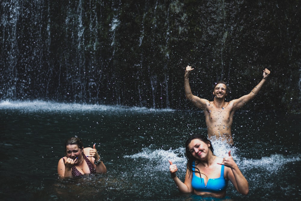 3 women in blue and black bikini on water fountain