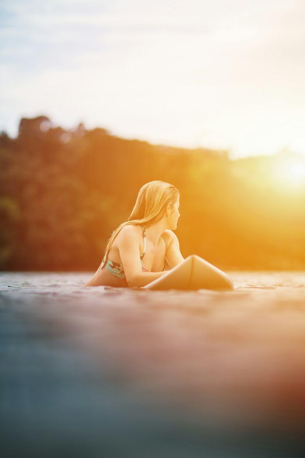 Frau im gelben Bikini liegt bei Sonnenuntergang am Strand