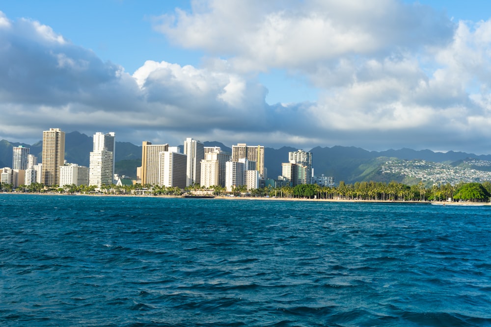 city skyline across body of water under blue and white sunny cloudy sky during daytime