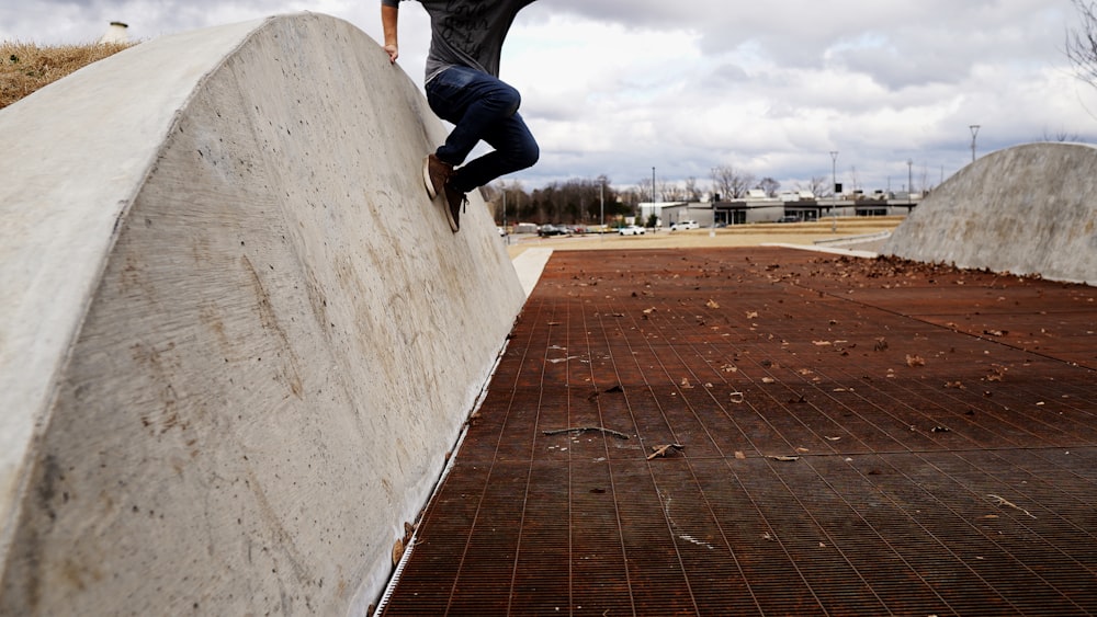 person in blue denim jeans and black shoes jumping on brown wooden dock during daytime