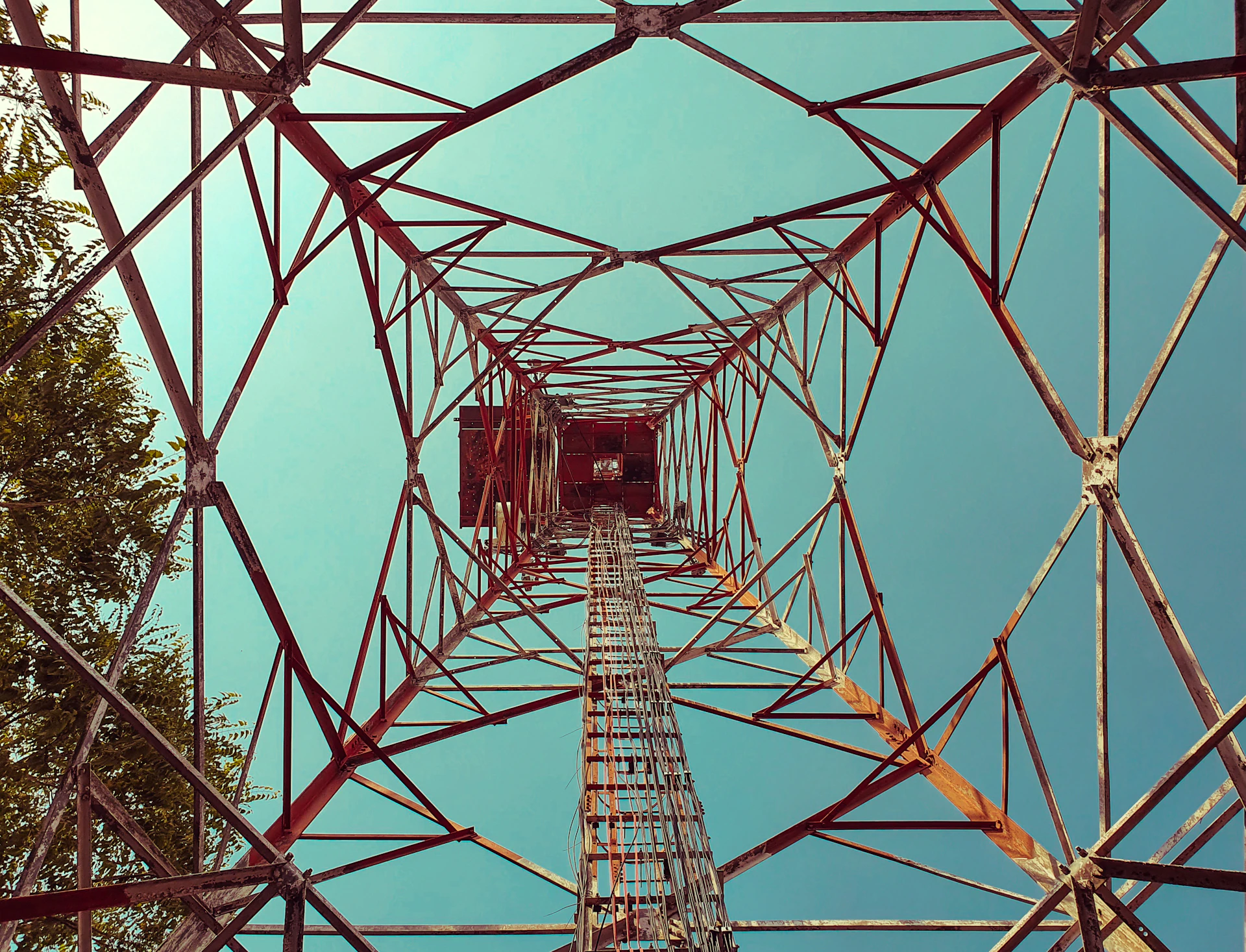 Orange-lit electrical transmission tower under a blue sky, representing Berjos Limited's electrical services