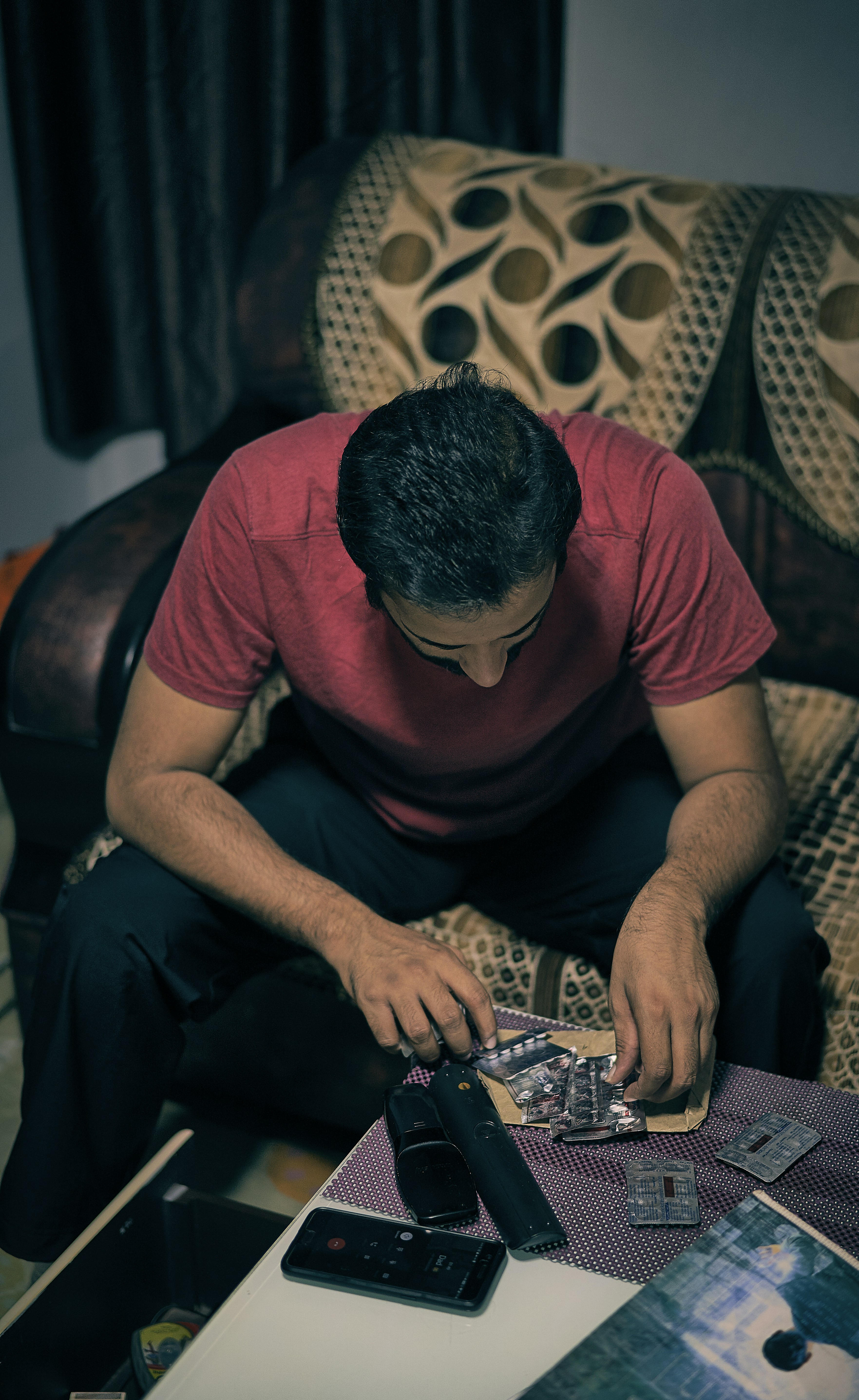 man in red crew neck t-shirt and black pants sitting on brown and white sofa