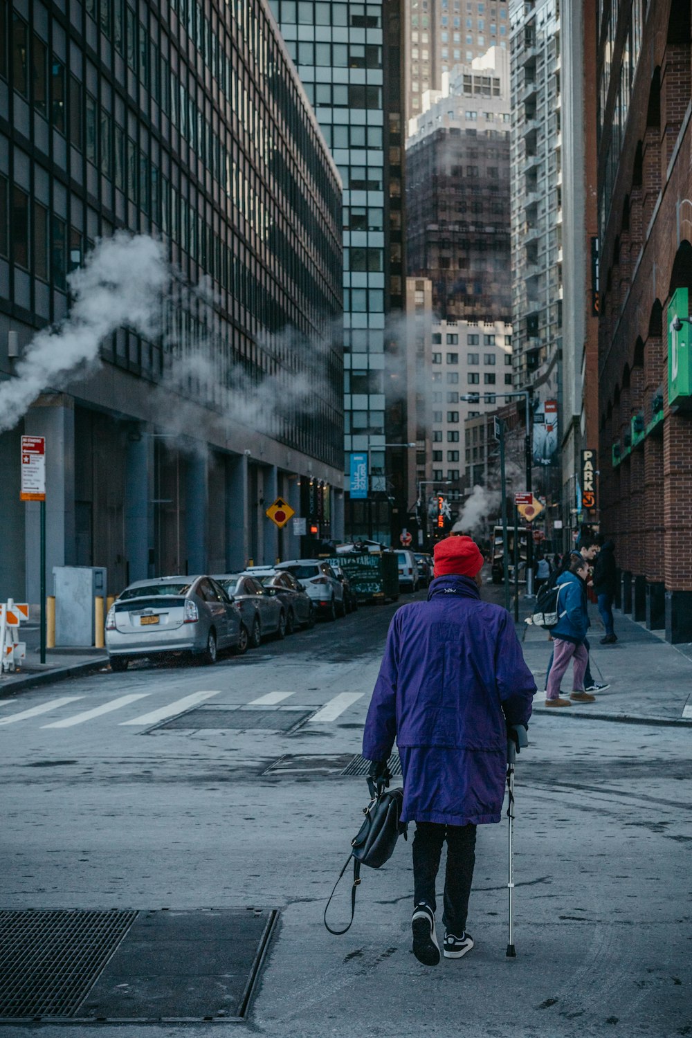 person in blue jacket walking on street with smoke